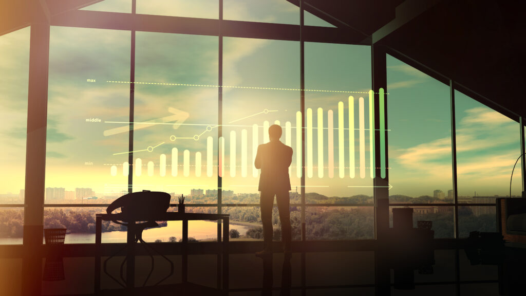 in a large office, a businessman looks at a growth graph at dawn.